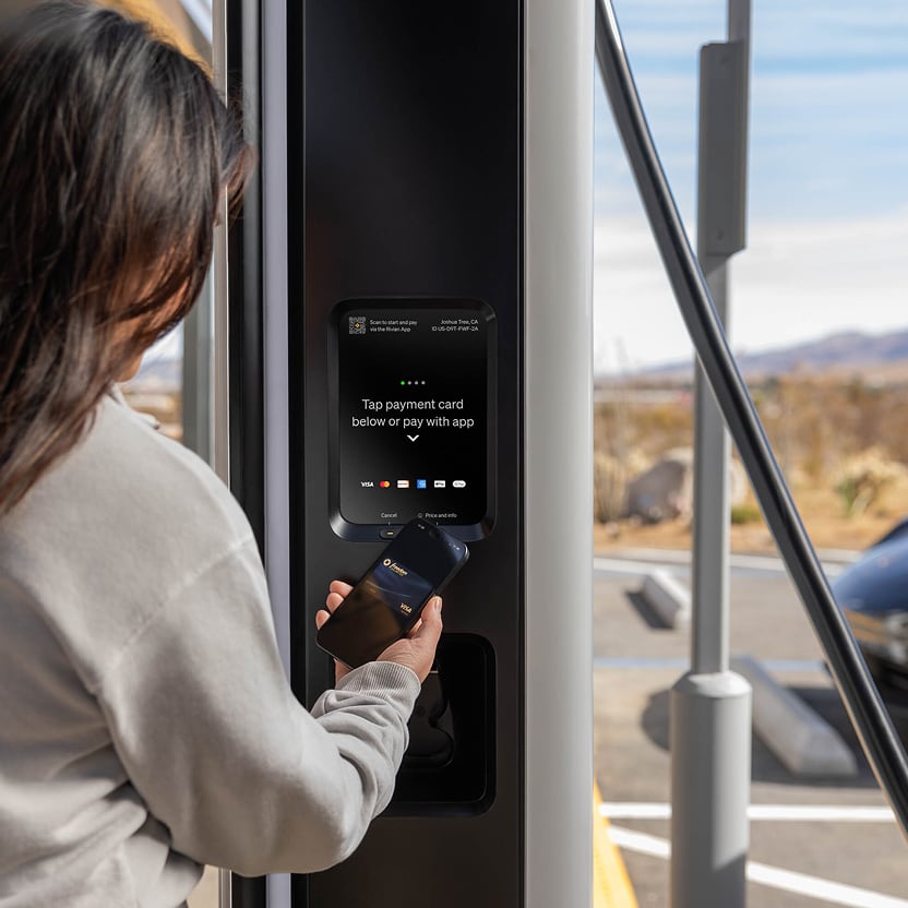A person using their phone to seamlessly pay at a Rivian Adventure Network charger.