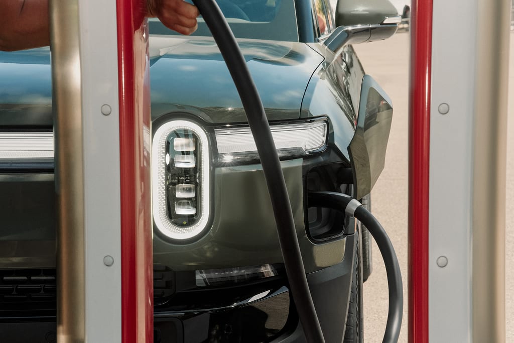 Public charger plugged into a Forest Green Rivian R1S electric SUV.
