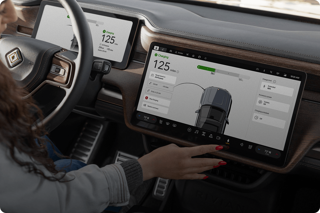 Woman with red nails taps a Rivian's infotainment display to view her charging session and range.