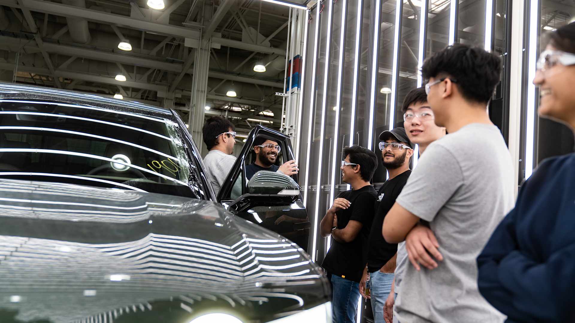 People standing near green Rivian 
