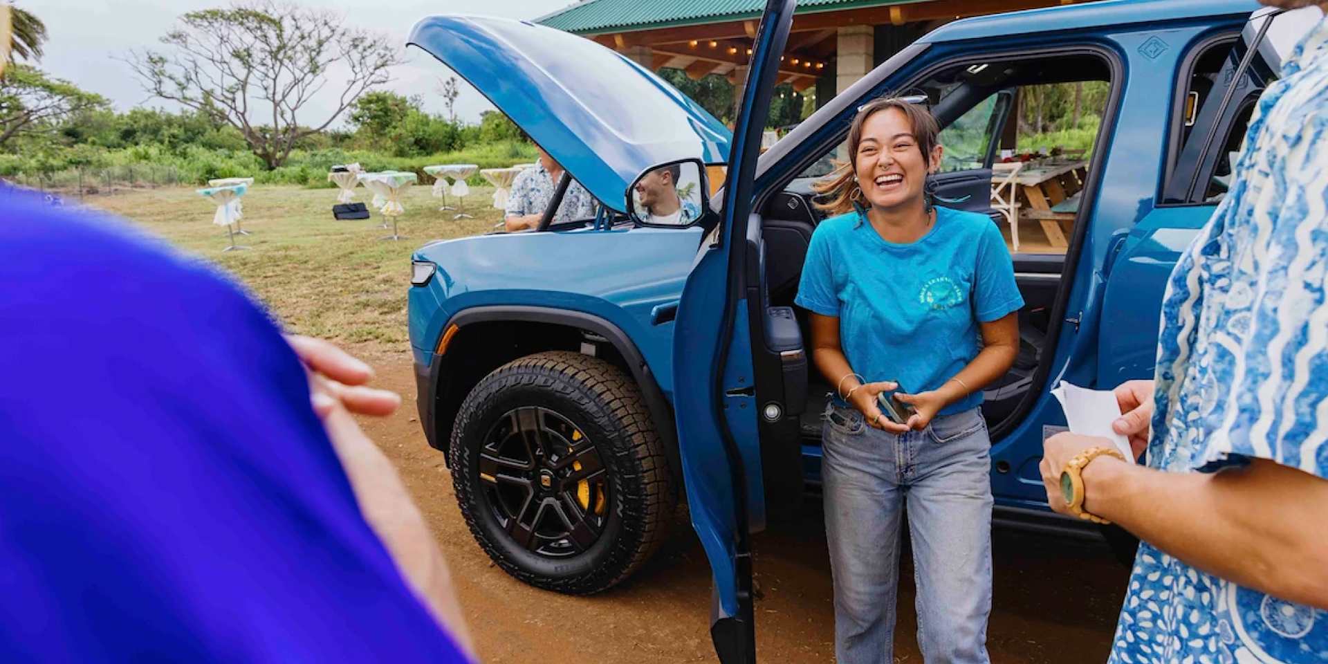 Girl laughing outside of blue rivian