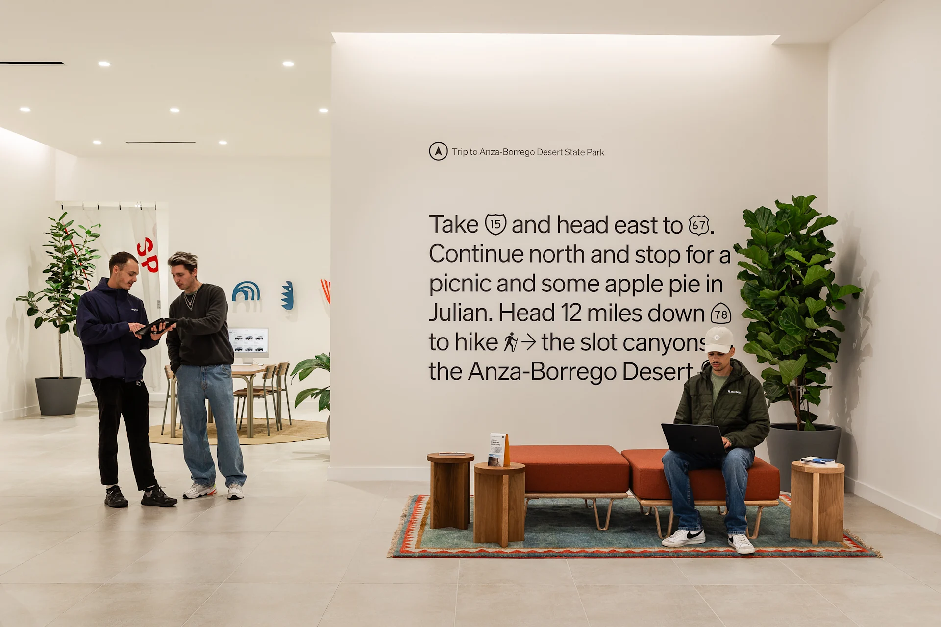 Three visitors talk and lounge inside the Rivian La Jolla space.