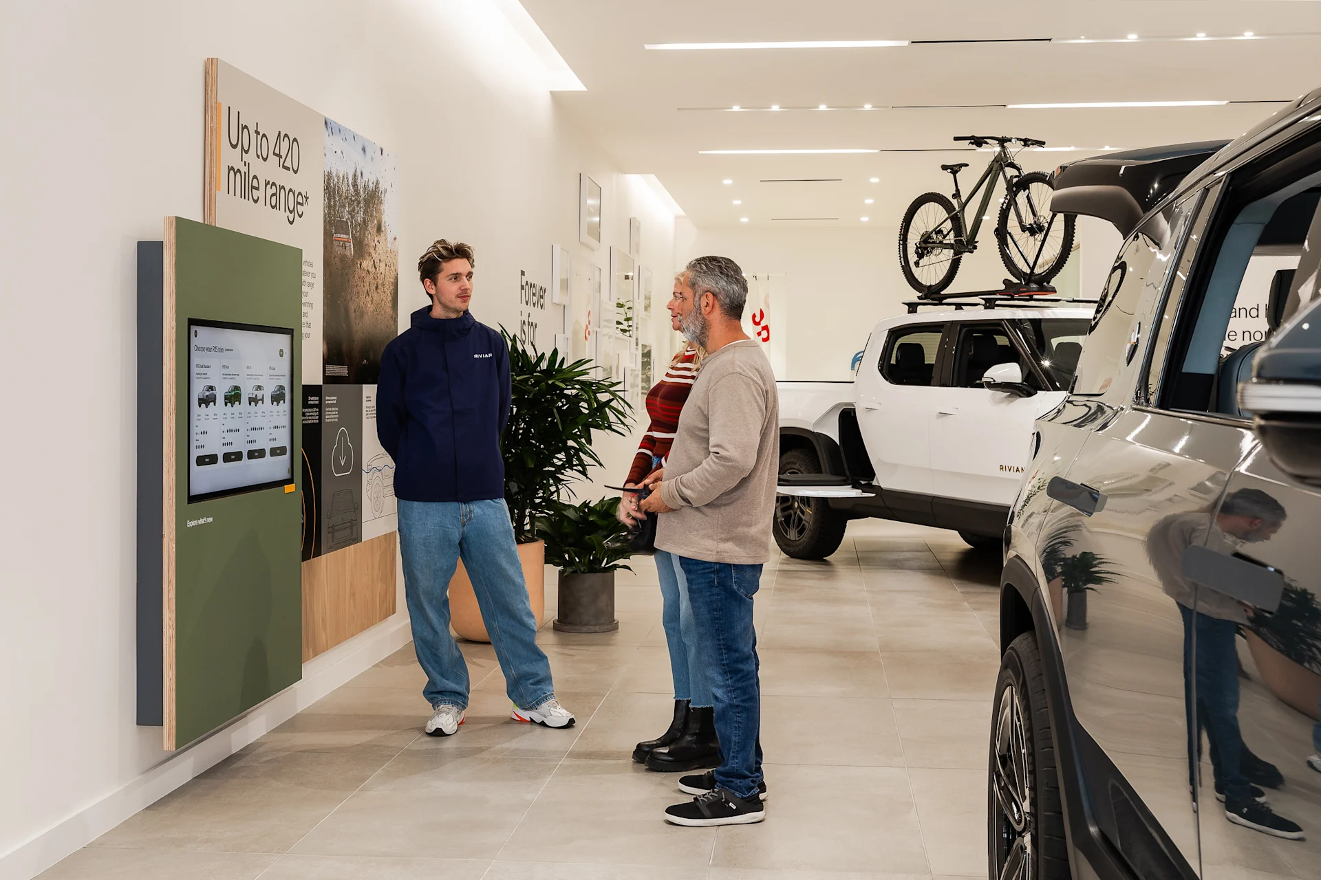A Rivian advisor talks with two customers, showing them how to build their own custom Rivian on the virtual vehicle builder.