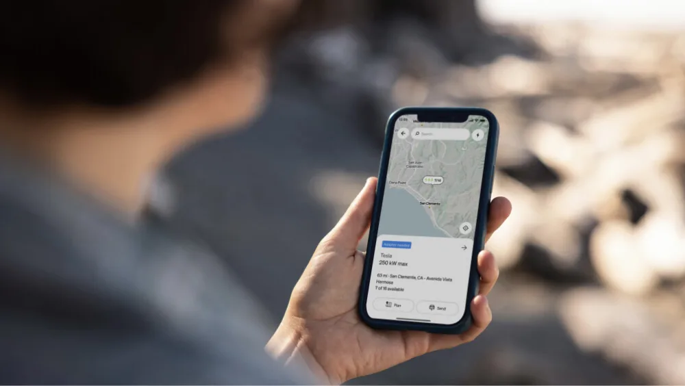 A person holding a mobile phone showing the Rivian App.
