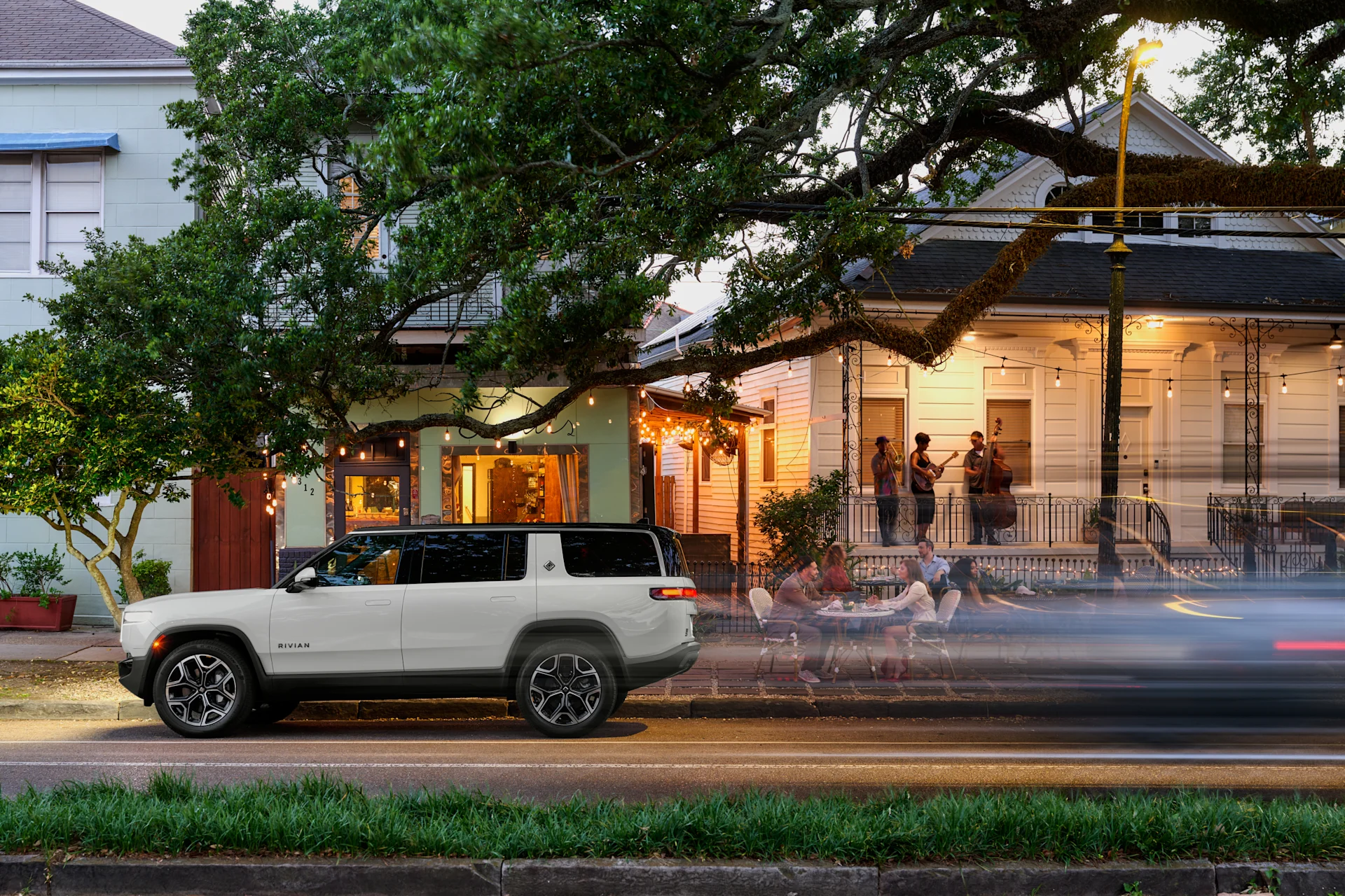 A Rivian R1 inside a Rivian space with people walking toward a city.
