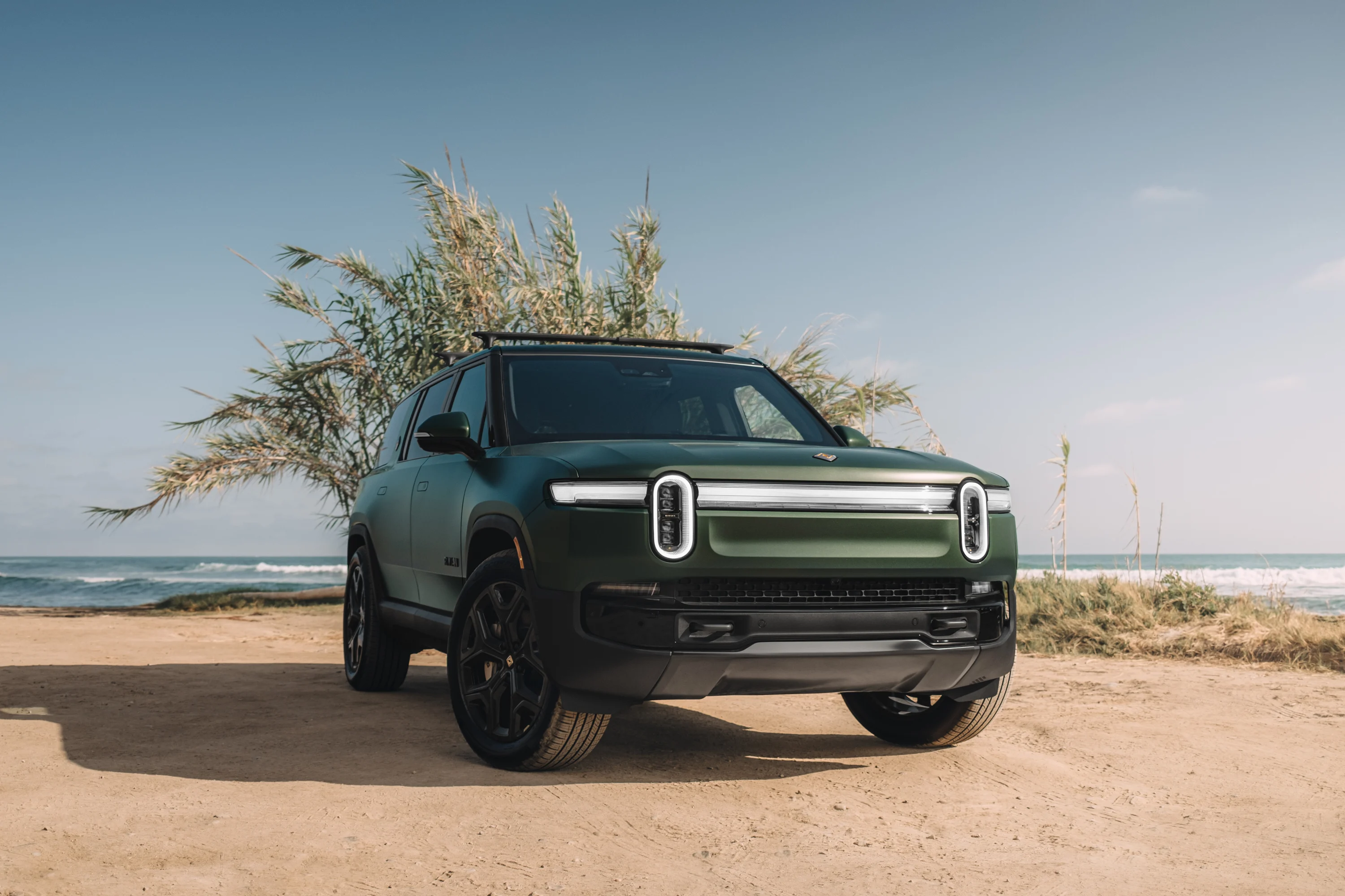 Rivian electric SUV with Road Trip Package accessories on the beach
