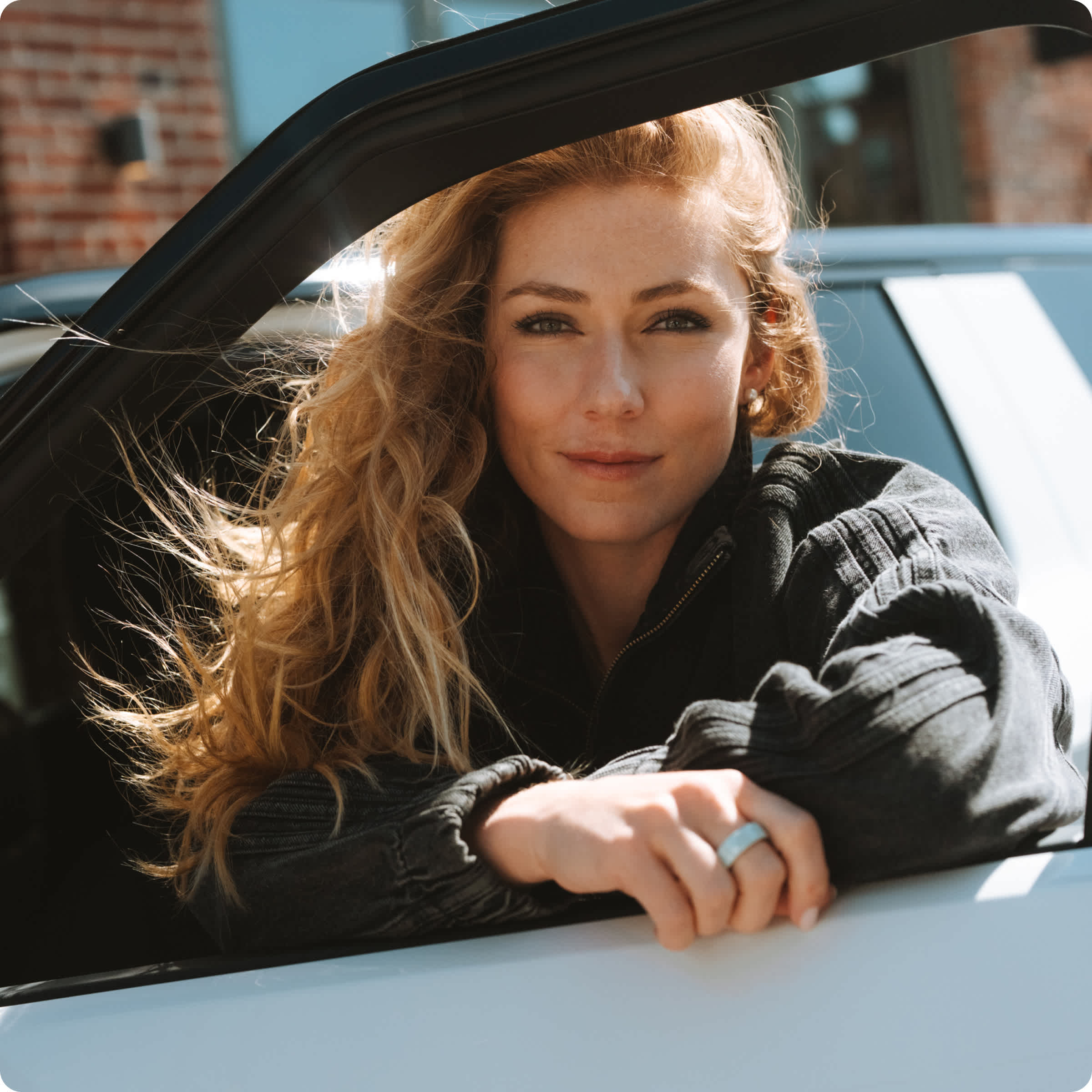 Mikaela Shiffrin leaning against the open driver door of a Rivian electric vehicle.
