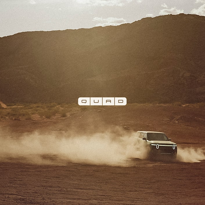 L'avant d'un véhicule électrique Rivian avec un épais nuage de poussière dans l'air.