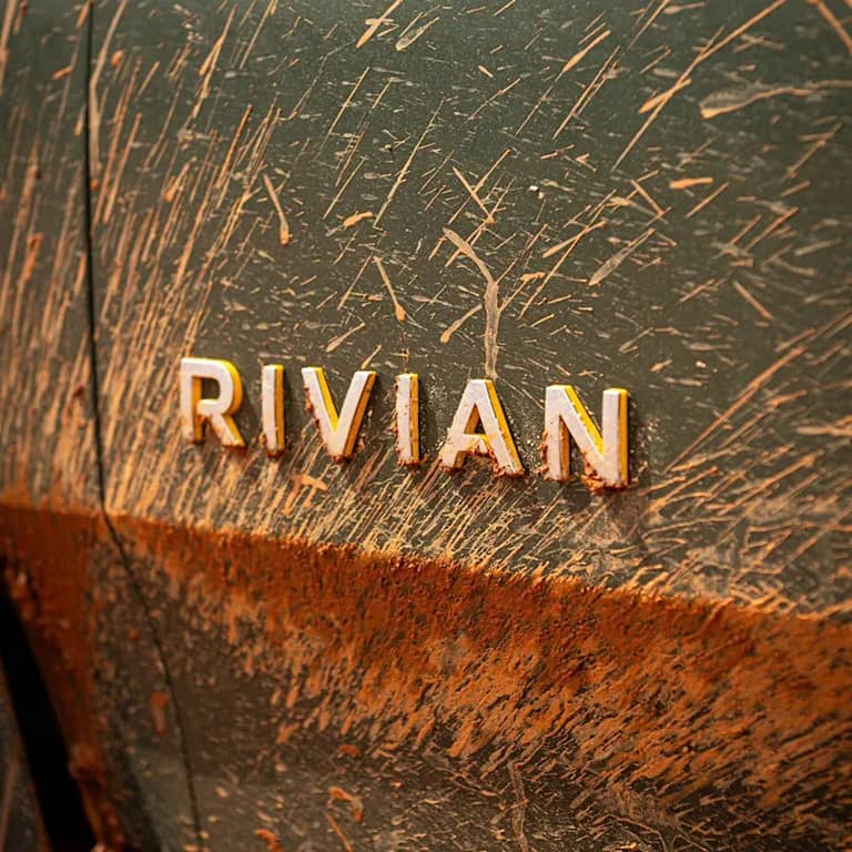 Rivian logo on a vehicle coated in dirt after off-roading