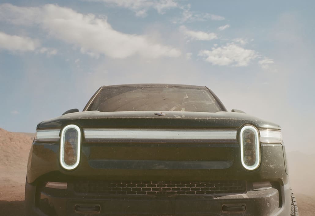 A close up view of the front of a Rivian electric vehicle. The car features the limited-edition Launch Green color way.