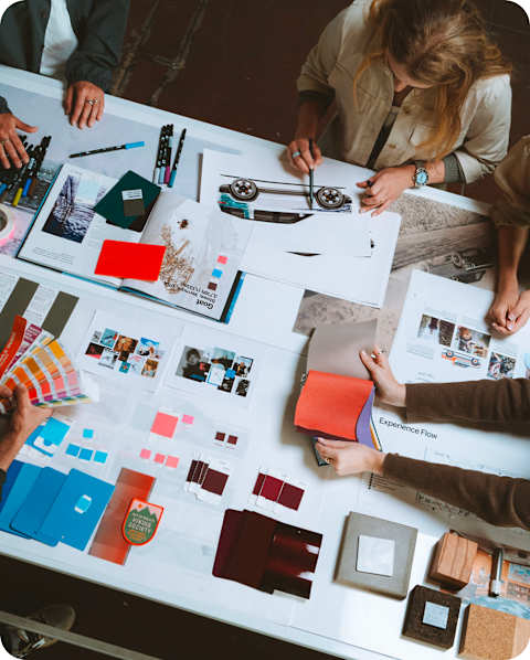 Aerial shot of Mikaela Shiffrin and three producers standing around a table reviewing blueprints and color swatches for the Performance House.