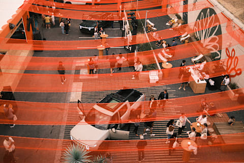An overhead view of an outdoor event space during the 2025 SXSW Electric Roadhouse, featuring two Rivian electric vehicles parked in a courtyard.