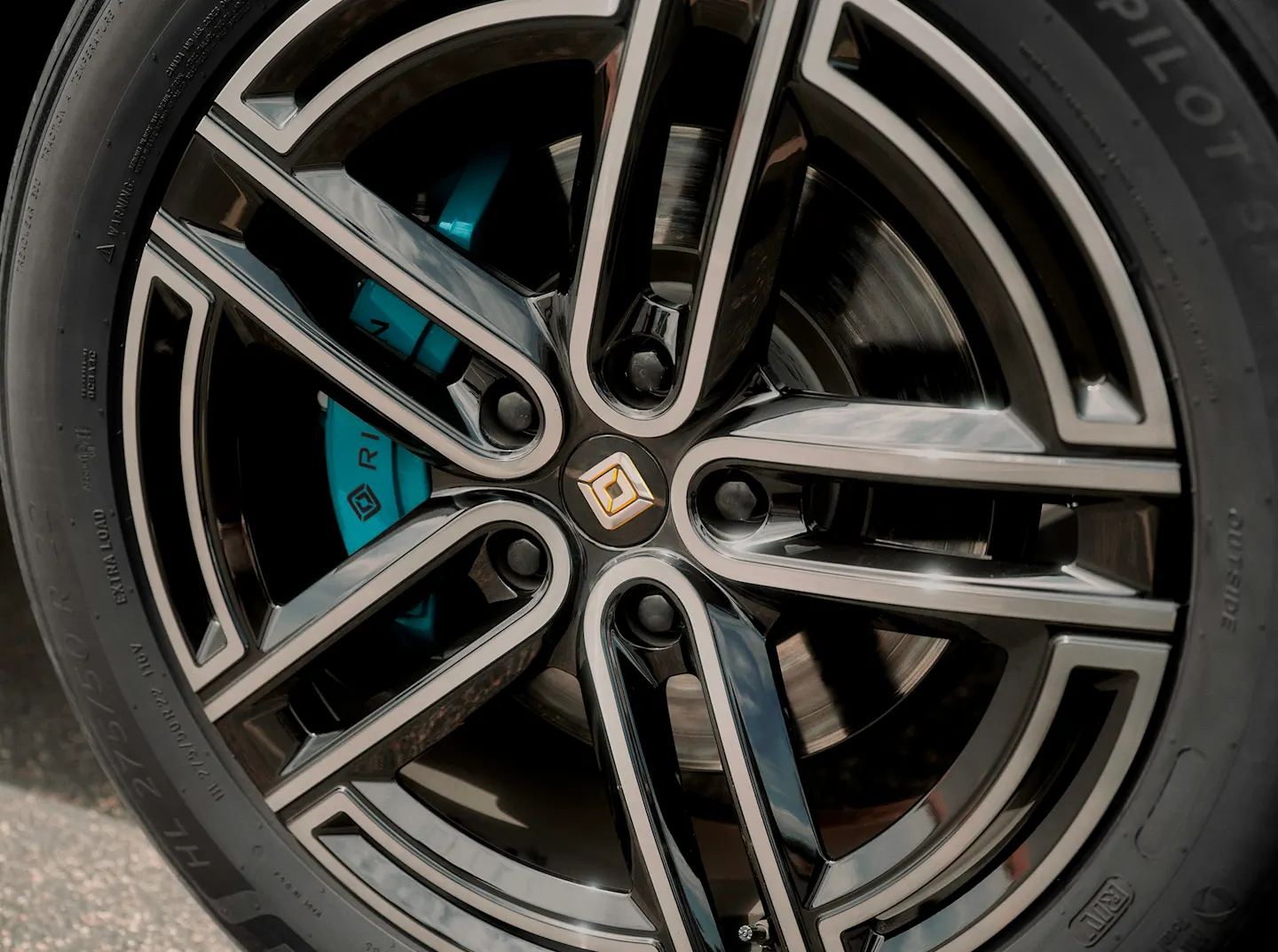 The wheels of a Rivian Quad motor electric vehicle. The 22" Super Sport wheels feature Laguna Blue calipers, an exclusive to Quad motor trims.