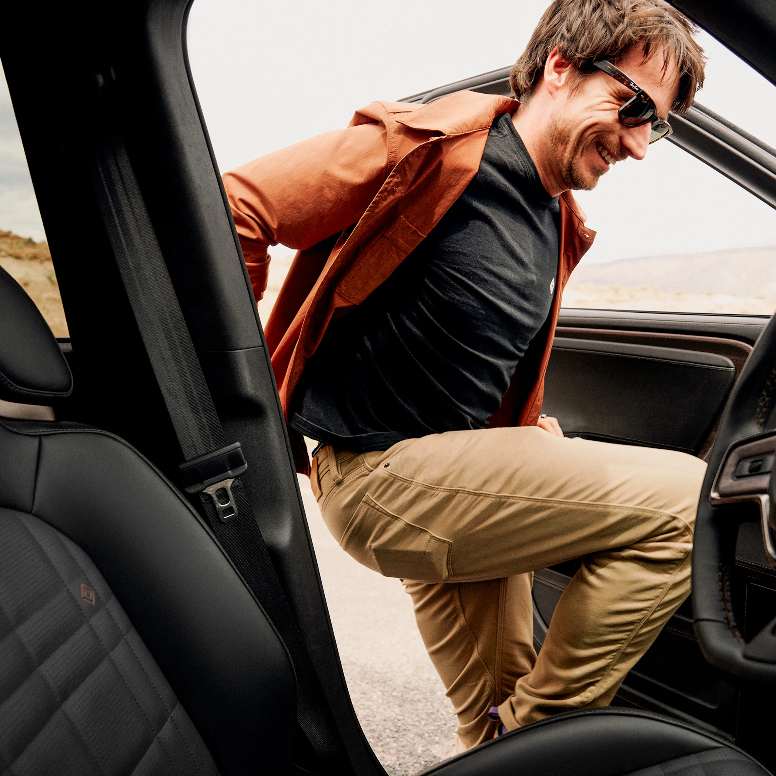 A person smiling as the enter the driving seat of a Rivian electric vehicle.
