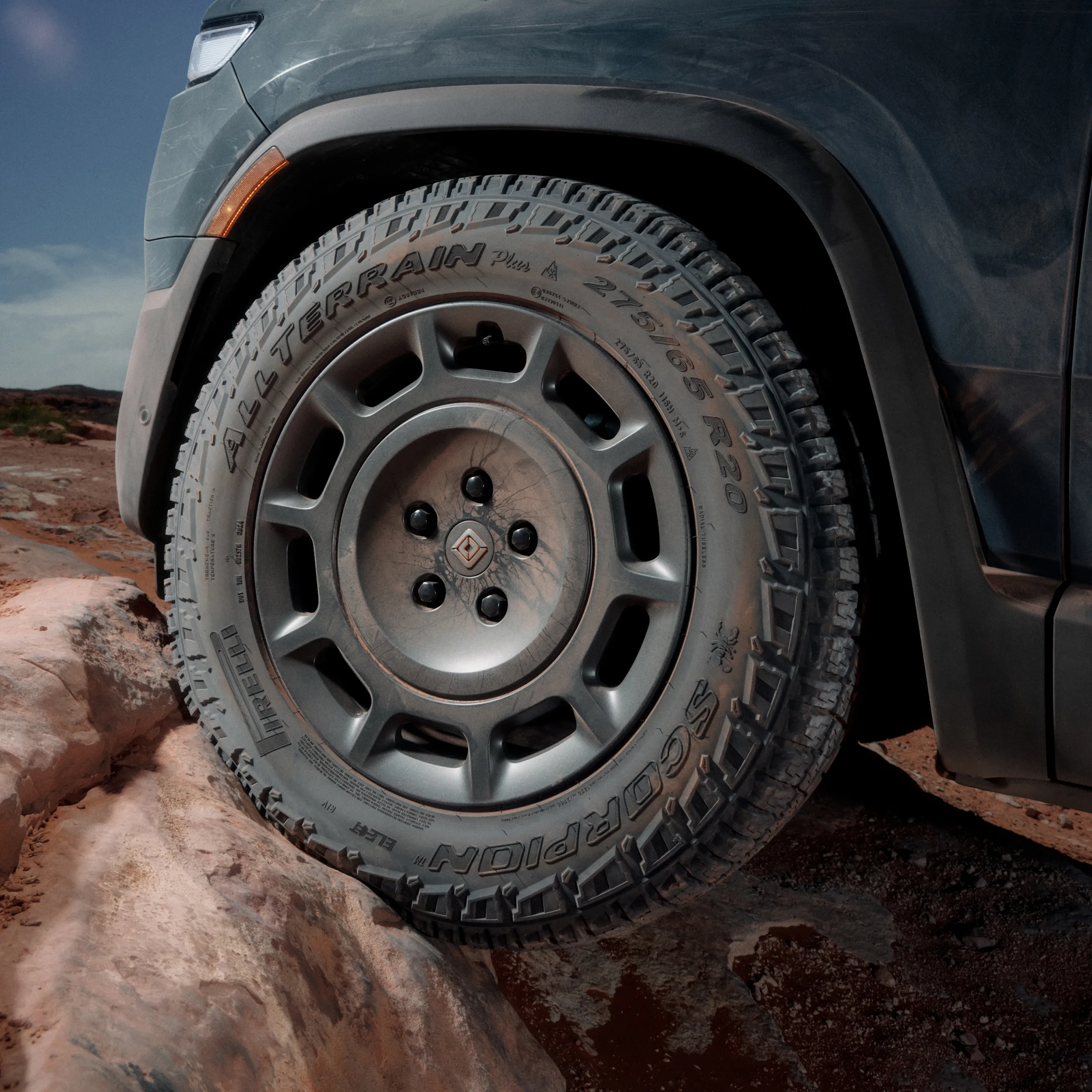 An action shot from a low point-of-view of the front driver side wheel. The wheel features rugged tires and 20” Dune Satin Graphite All-Terrain wheels. 