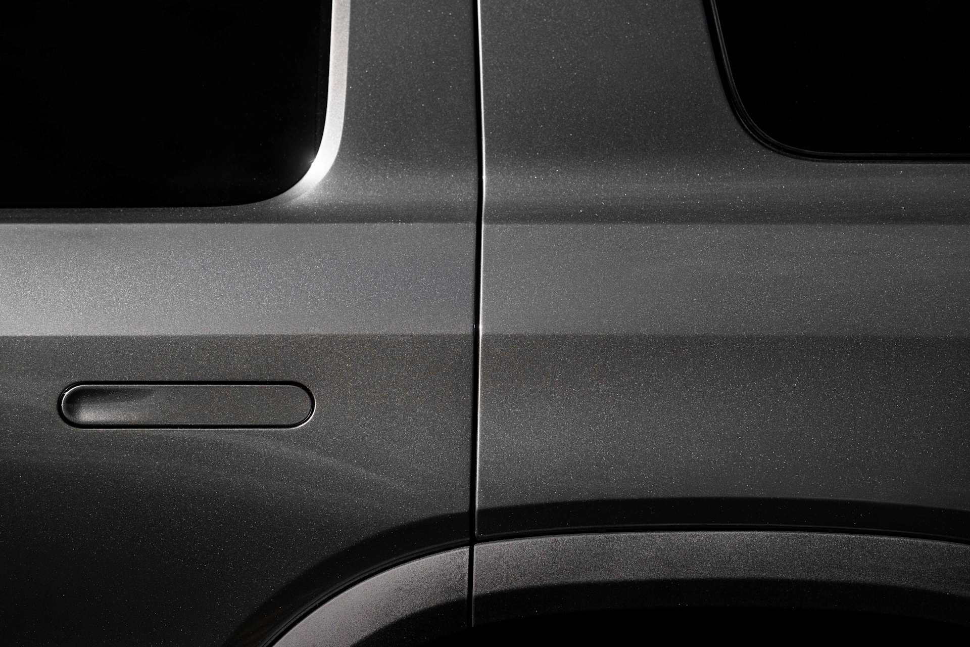 Close-up of a car door in "Half Moon Grey," showing the handle and the metallic sheen of the paint.