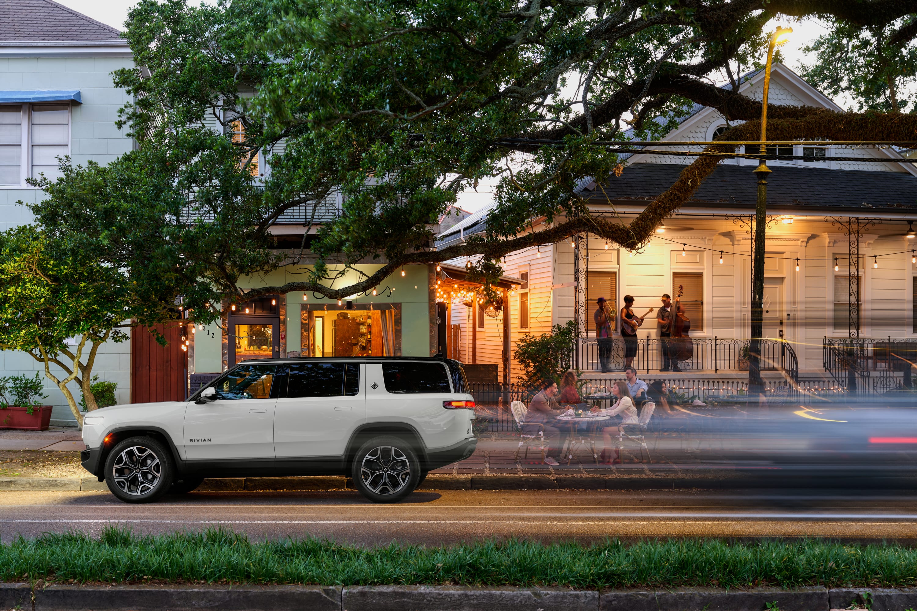 A Rivian R1 inside a Rivian space with people walking toward a city.