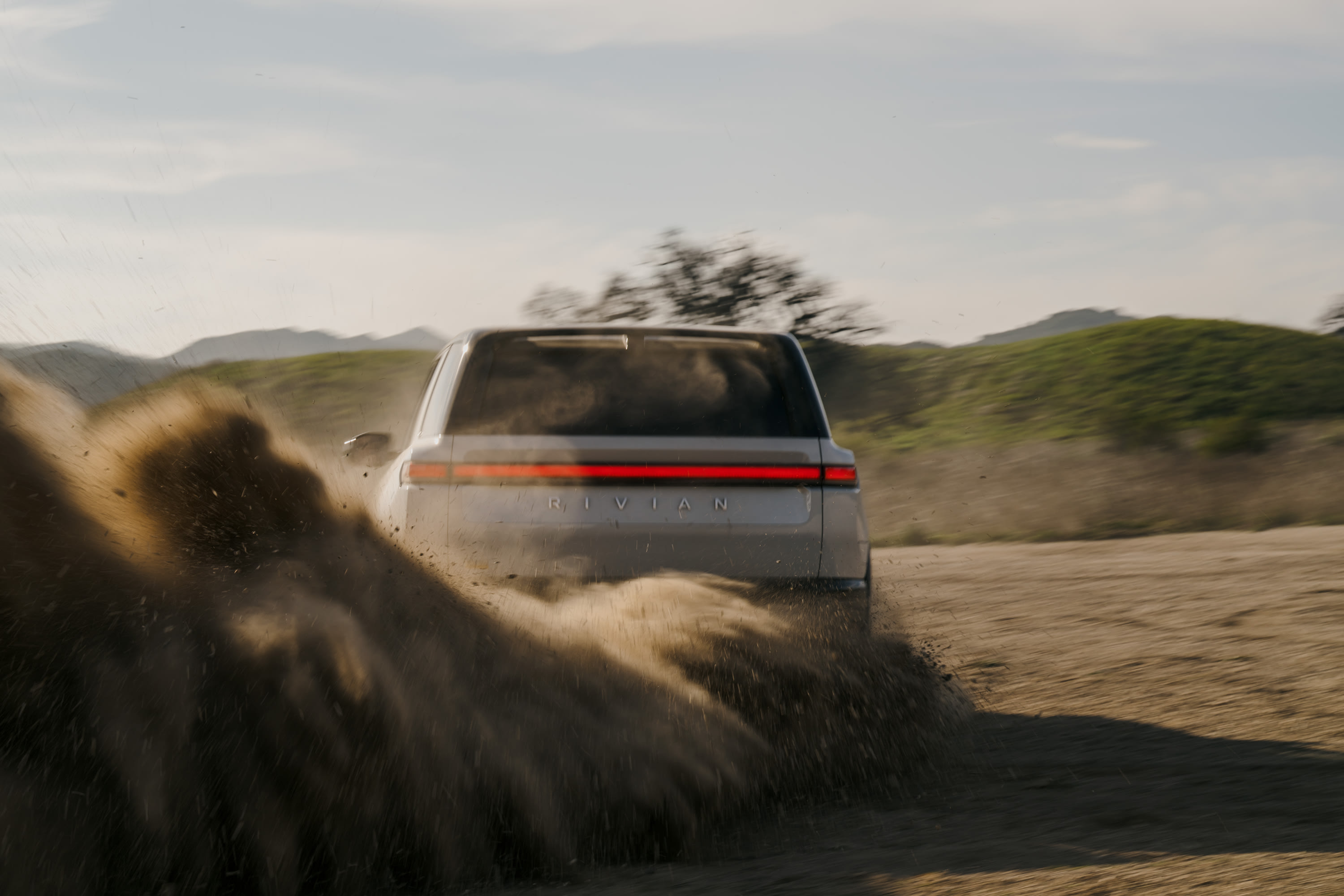 Rivian R2 electric SUV on a mountain trail at golden hour